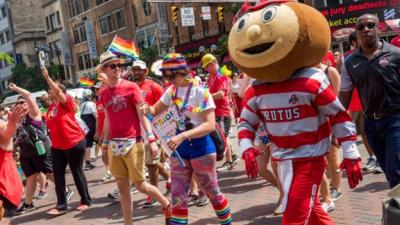 Brutus mascot at Pride parade with people wearing rainbow colors and red Ohio State shirts