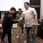 Dr. John Holmes shaking hands with student