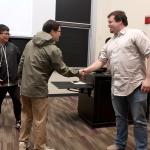 Dr. John Holmes shaking hands with student